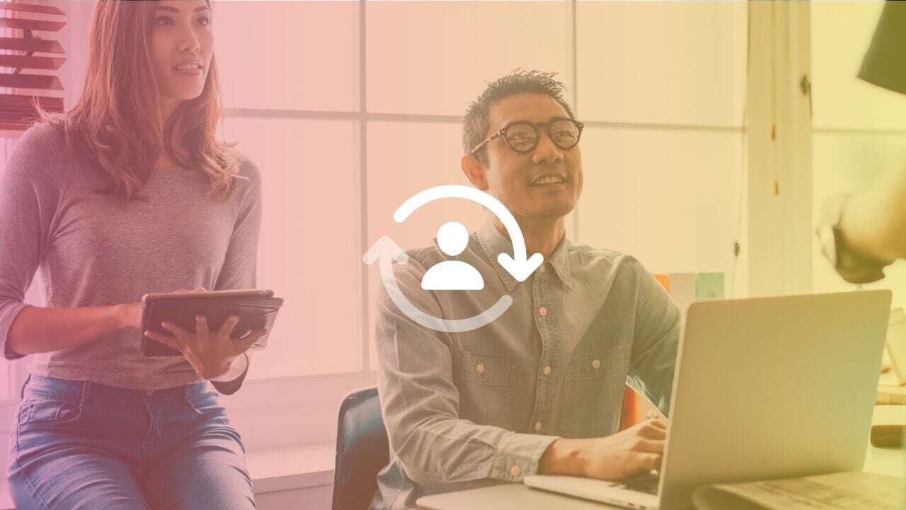 Man with glasses sitting at a desk with a laptop