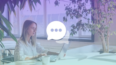 A woman sat at a desk in an office, typing on a laptop