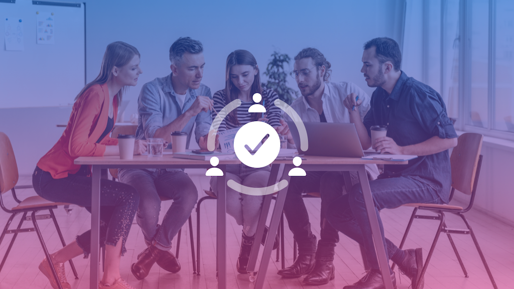 People gathered around a desk with coffee and laptops