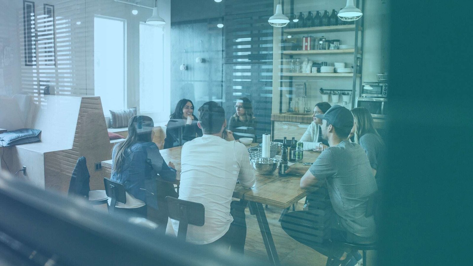 Employees in a meeting room, gathered around a wooden table