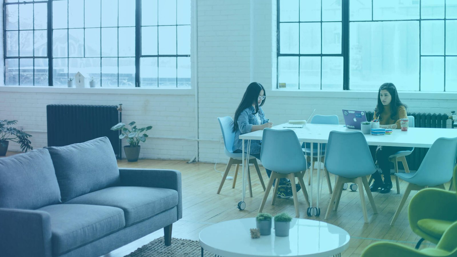 two women working on laptops at an office using AI in internal communications