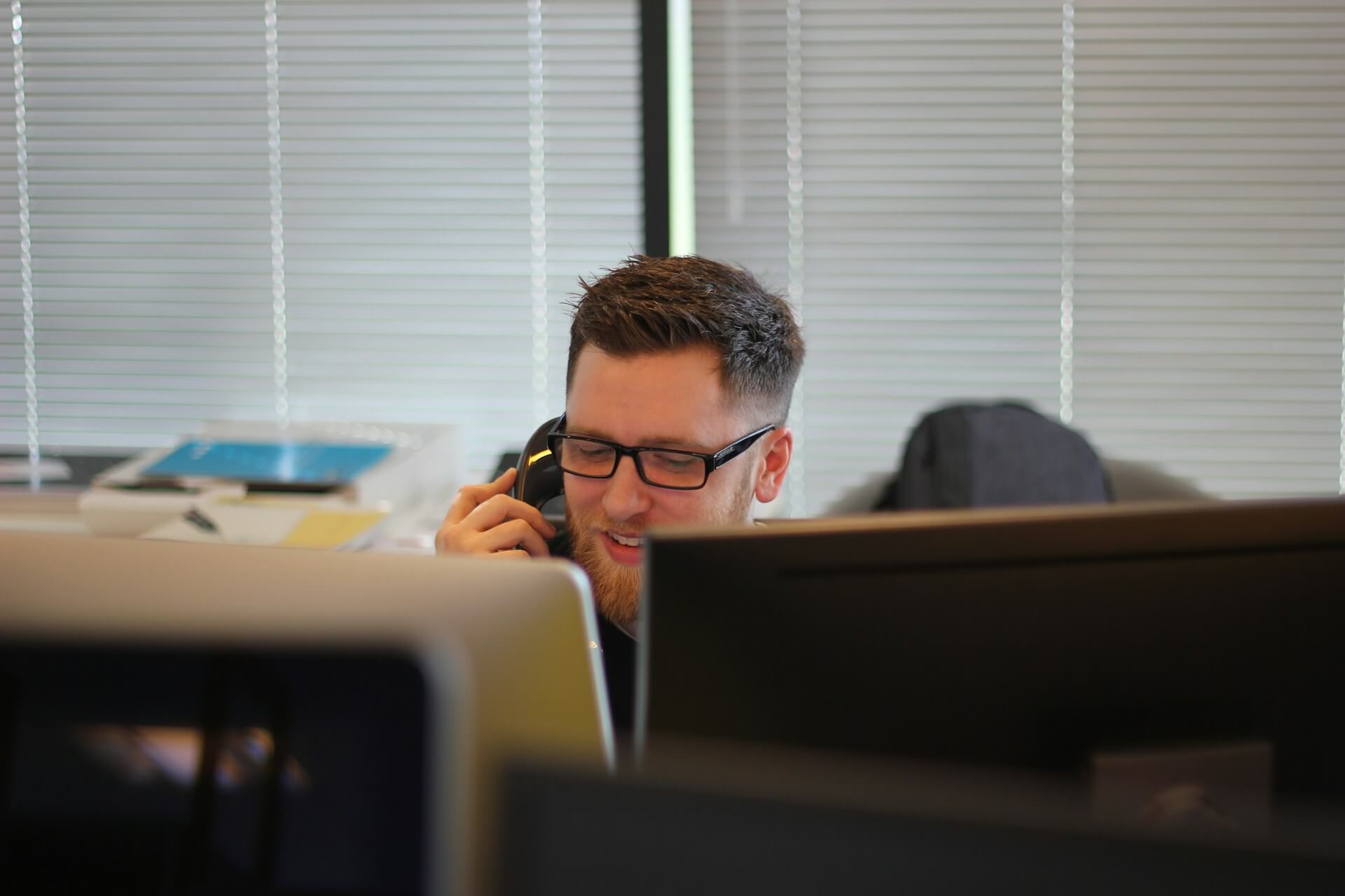 man working at two screens on the phone